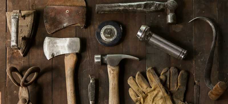 Old tools arranged and hung on a rustic wall